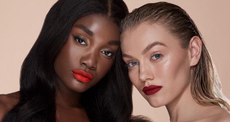 Two models wearing different shades of Emolyne lipstick in red
